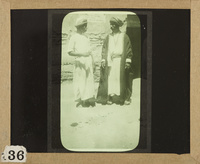 Two men standing on the doorway in a street of an Arab village