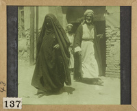 Two men and a woman on the doorway in a street of an Arab village